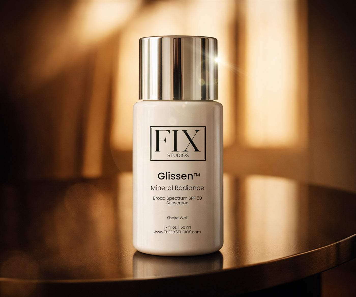 A bottle of Fix Studios medical-grade Glissen™ Mineral Radiance SPF 50 rests on a highly polished table with the morning light beaming through a window in the background
