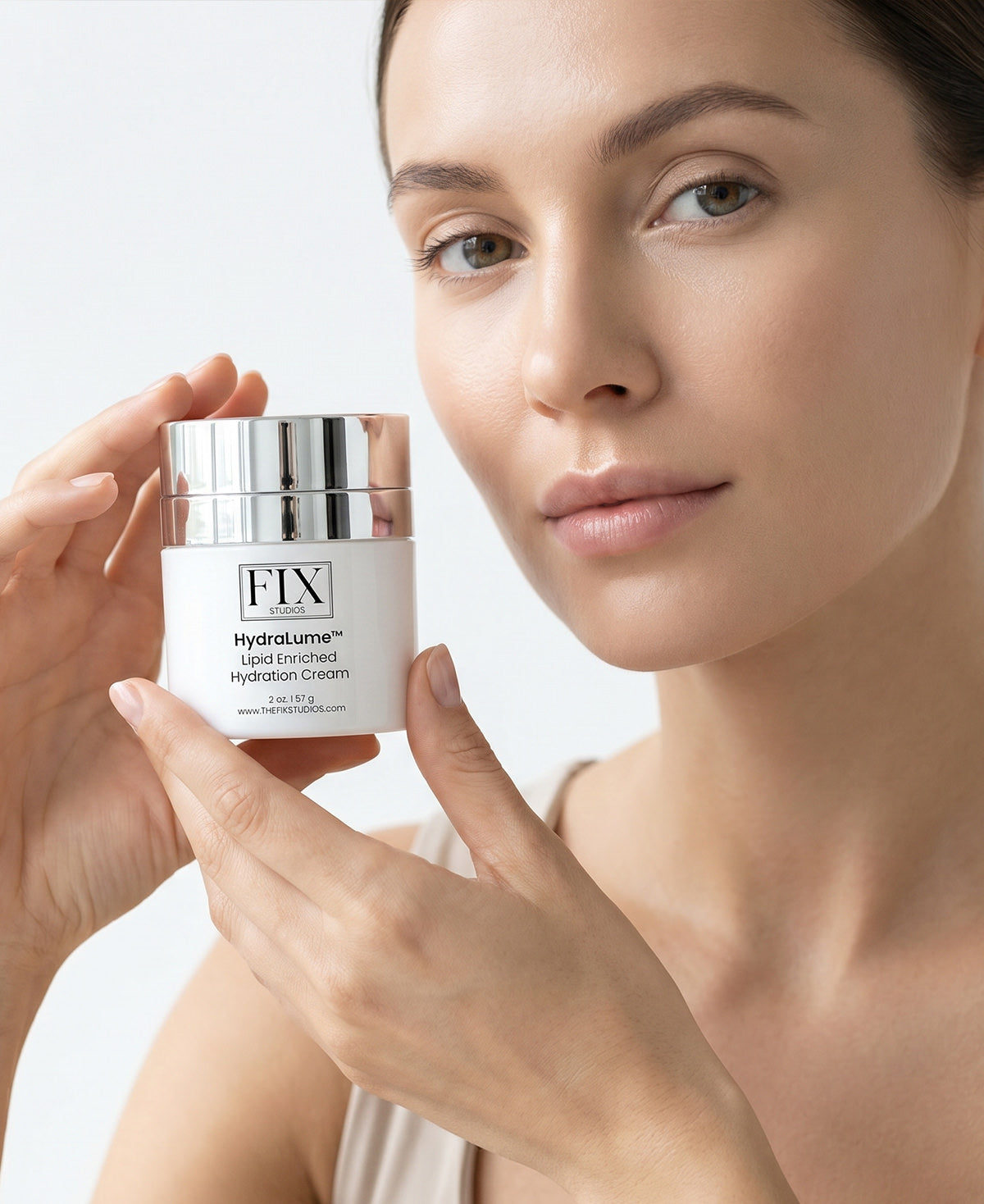 Close up of a woman holding Fix Studios medical-grade HydraLume™ Lipid Enriched Hydration Cream