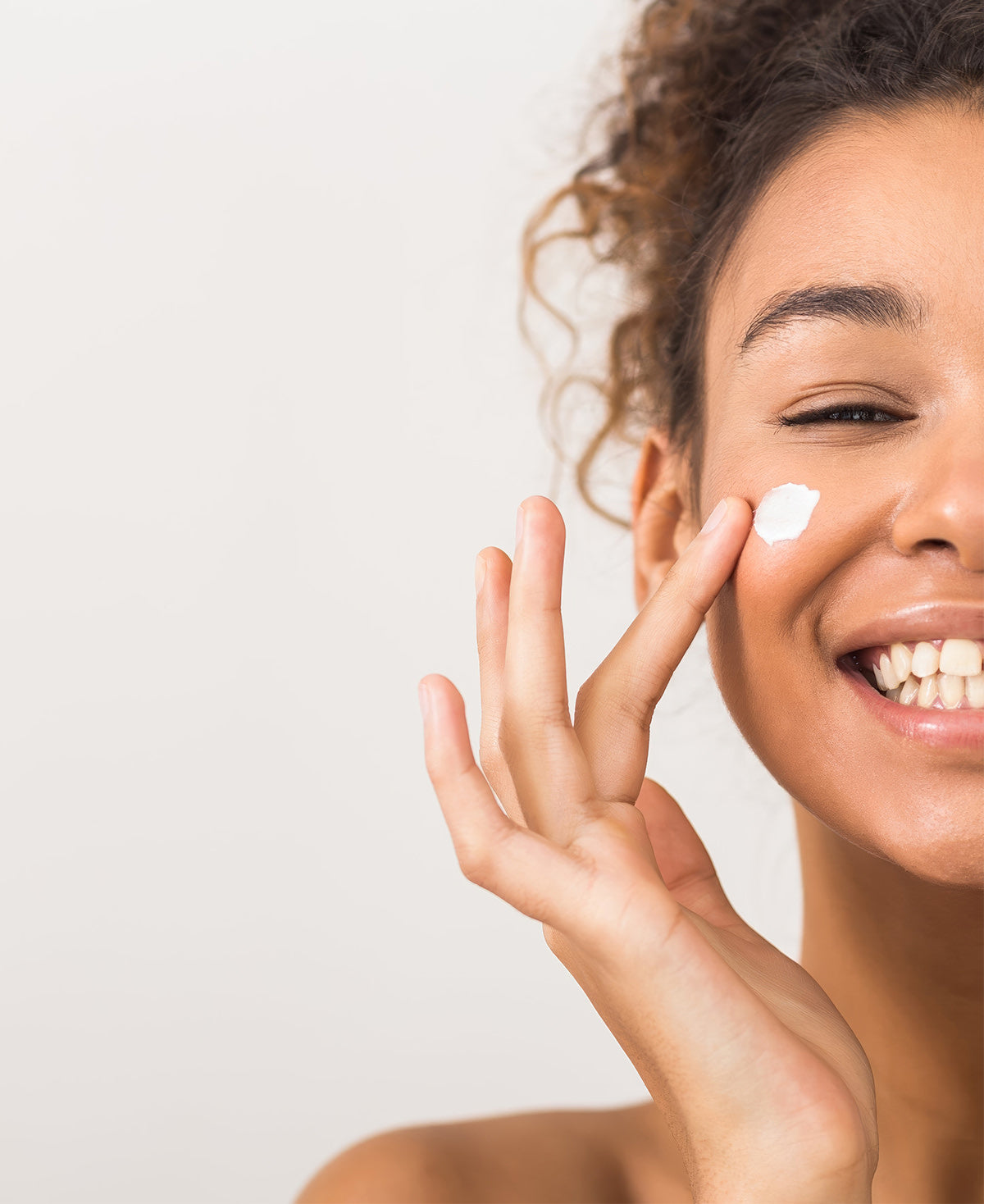 A beautiful woman applies Fix Studios medical-grade HydraSoothe™ Lightweight Soothing Moisturizer to her face