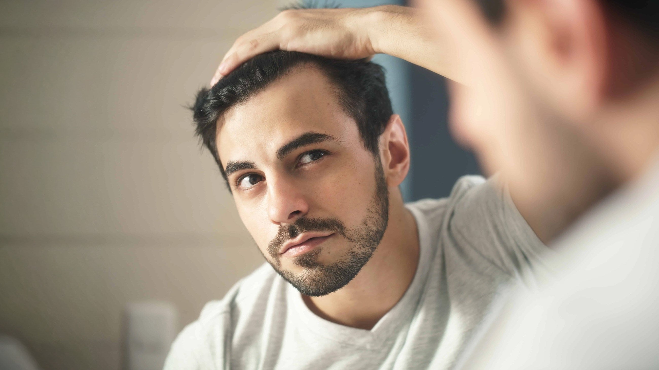 A man looks in the mirror at his hair after receiving prp/prf hair restoration cincinnati treatments
