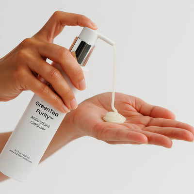 A woman pumps a bottle of medical-grade Fix Studios GreenTea Purity™ Antioxidant Cleanser into the palm of her hand