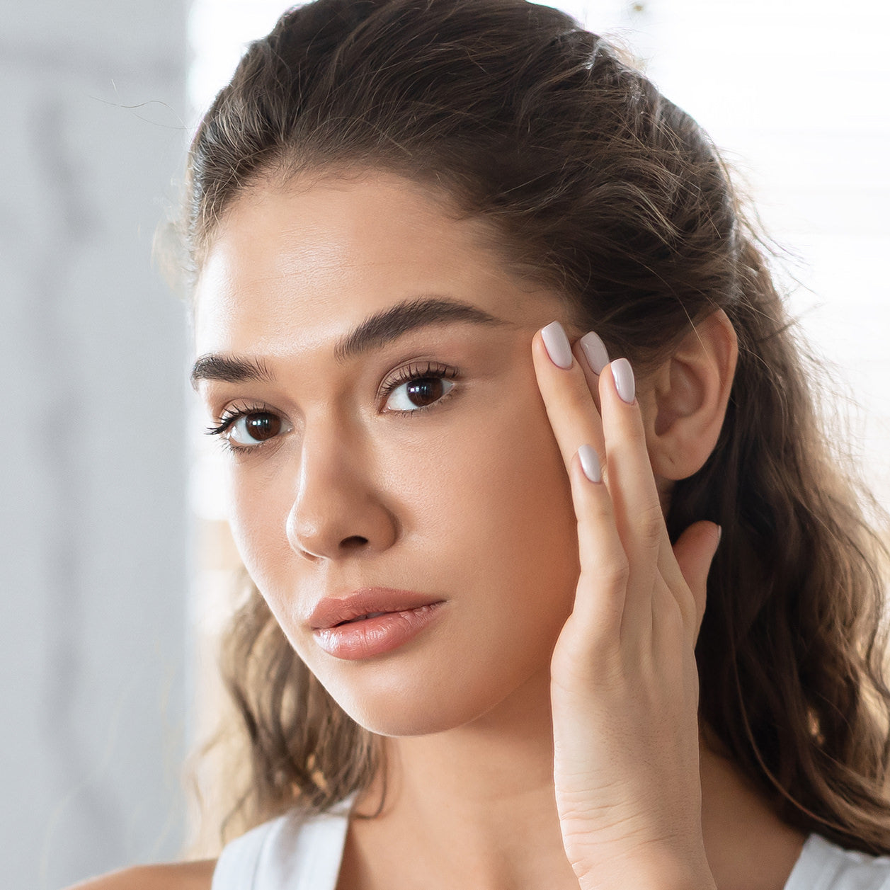 a young beautiful woman examines her face in the mirror after acne treatments at Fix Studios medspa in Cincinnati Mason OH